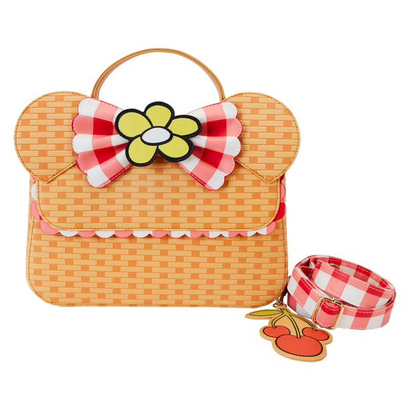 Loungefly Disney crossbody bag made from a material that looks like a woven picnic basket. The crossbody bag has 3D Minnie Mouse ears and a gingham bow with a yellow flower on it. It also has a cherry bag charm attached. The bag sits against a white background. 